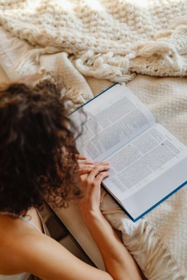 Women sitting on the floor reading the bible which is placed on the bed